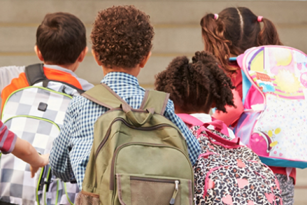 Four children running with backpacks.